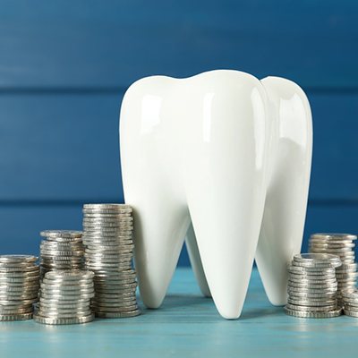 A large model tooth surrounded by silver coins