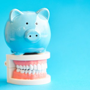 A piggy bank sitting on top of mock dentures 