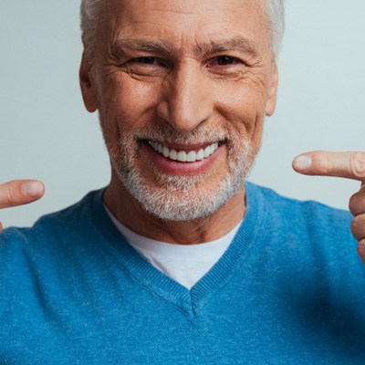 smiling man pointing to his mouth 