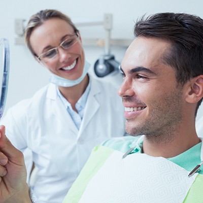 Male dental patient holding mirror