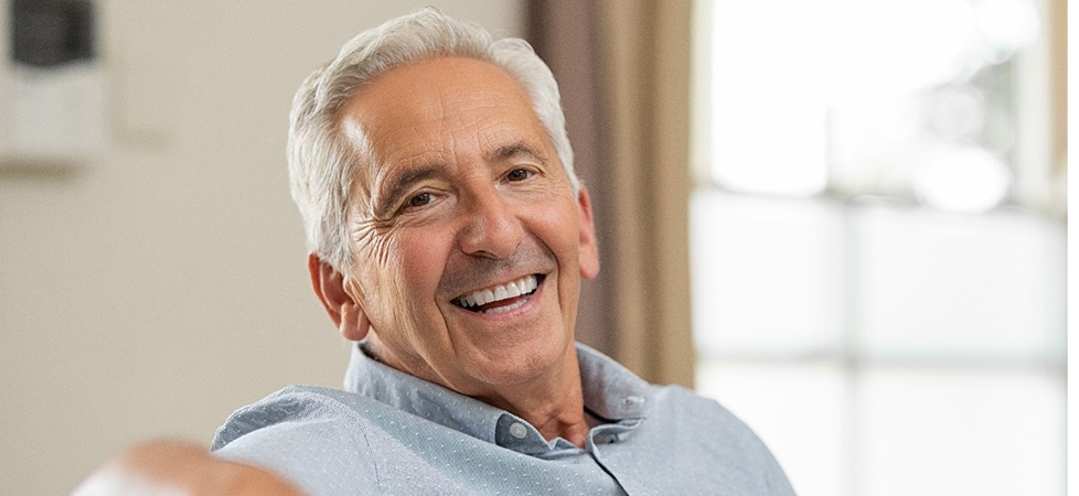 Senior man leaning back on his couch and smiling