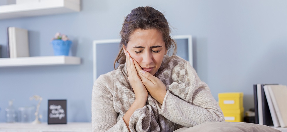 woman holding cheek in pain