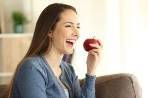 Woman smiling, eating an apple