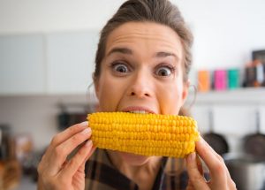 happy woman bites a corn cob